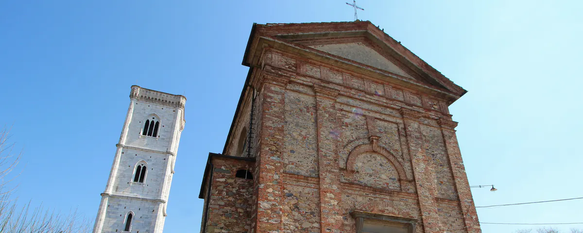 La chiesa di San Lorenzo Martire a Orentano: la facciata in pietra e mattoni e, a sinistra, il campanile bianco